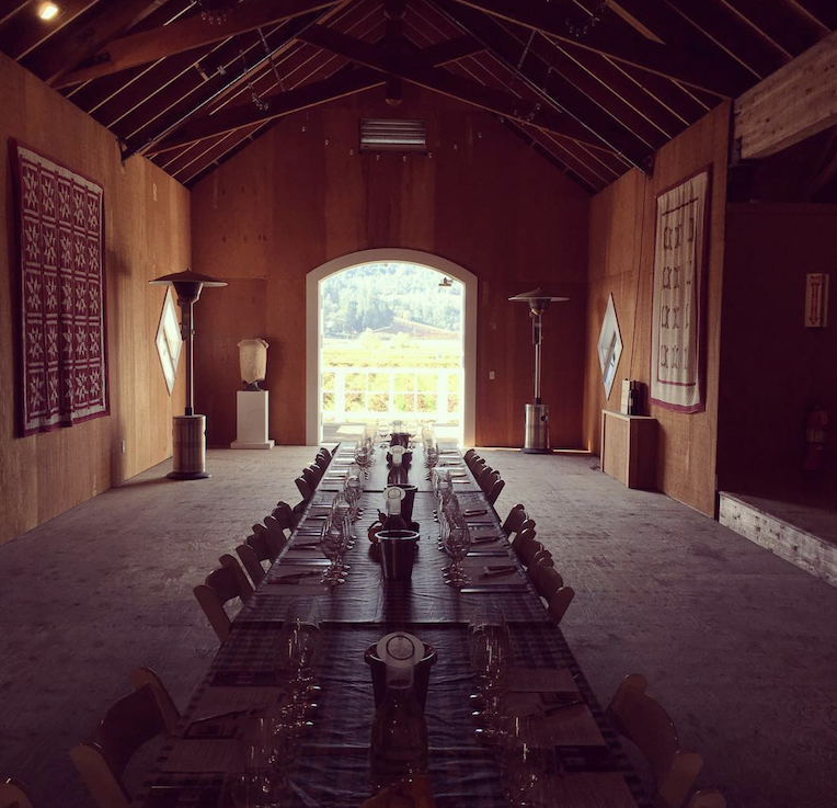 Tasting barn with wine glasses and open door looking on vineyards and mountains